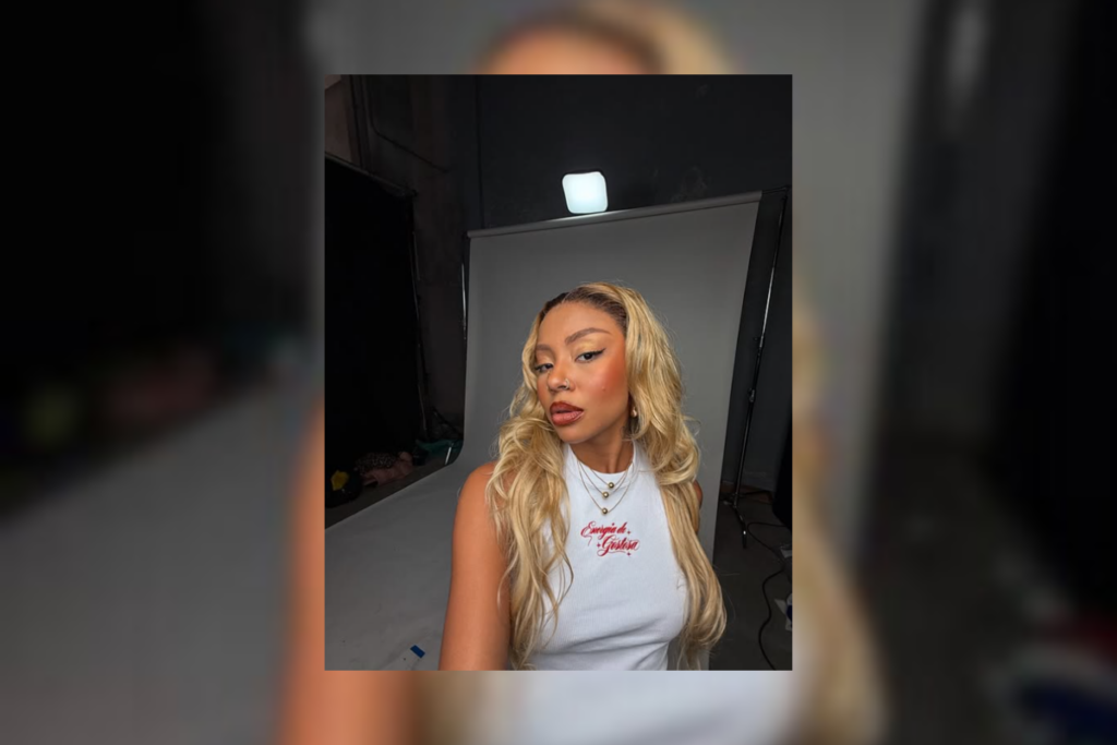 Mulher com cabelo louro liso e usando uma regata branca 